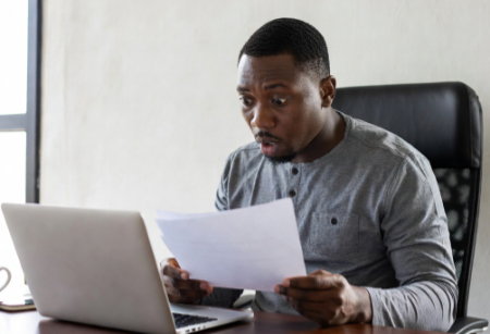 black male sitting at desk holding document surprised image created by Grok AI