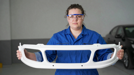 especialista en carrocería sosteniendo un parachoques de plástico generated with Z-Image